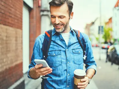 man on phone smiling while holding a coffee