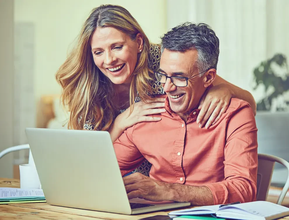 couple smiling while looking at their computer