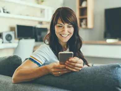 women smiling while looking at her phone