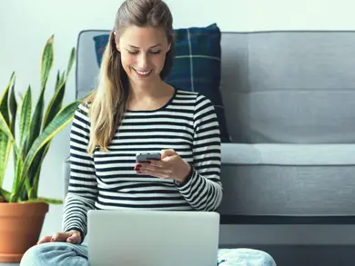 a women on her phone with her laptop in her lap