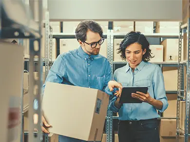 co workers looking at a tablet while holding a box