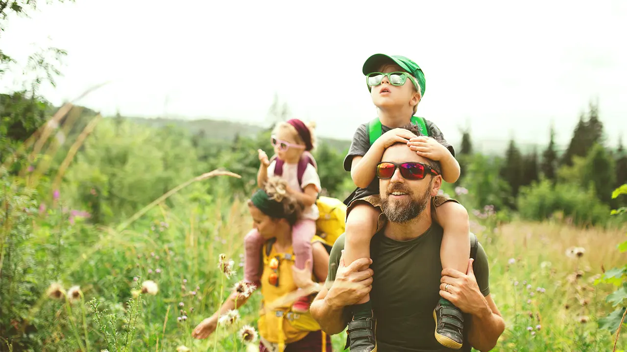 family of four on a midday hike surrounded by grass and trees