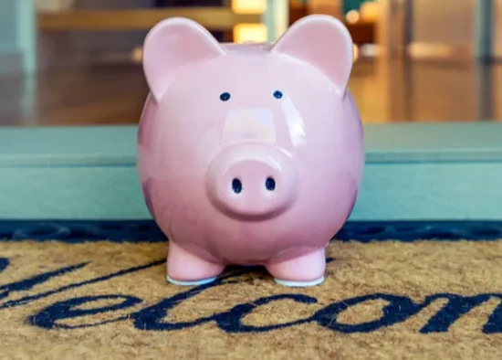 A piggy bank on the welcome mat of a home.