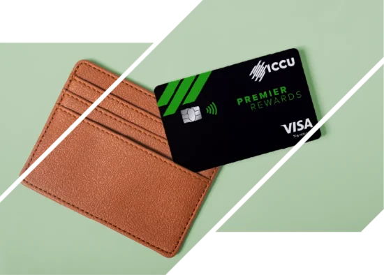 An ICCU Premier Rewards credit card beside a brown wallet on a green background.