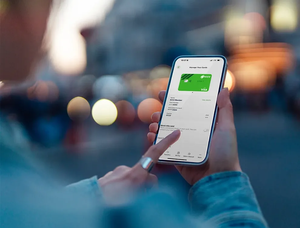 A person holding a smartphone with the ICCU eBranch app open