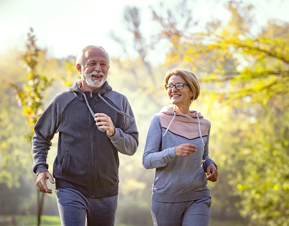 Una pareja de ancianos corriendo juntos al aire libre.