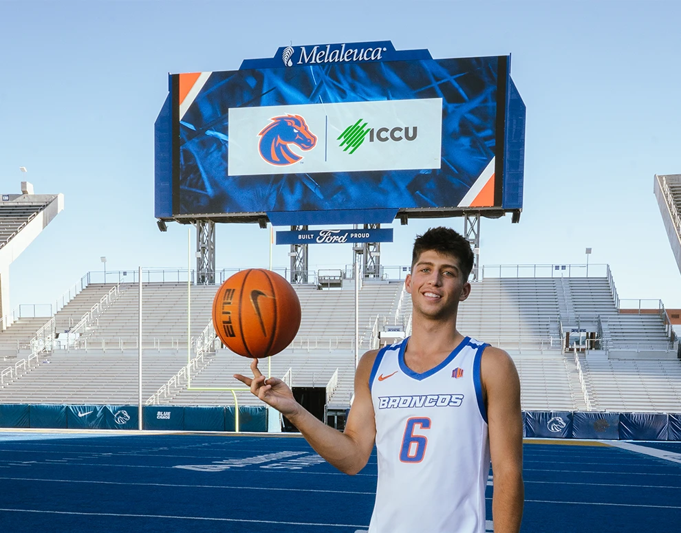 Pearson Carmichael stands in front of a jumbotron displaying the Boise State Broncos and ICCU logos.