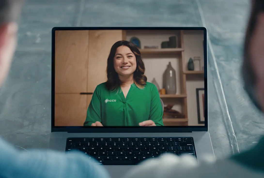 ICCU agent providing customer support via video chat, wearing a headset and smiling at the screen.