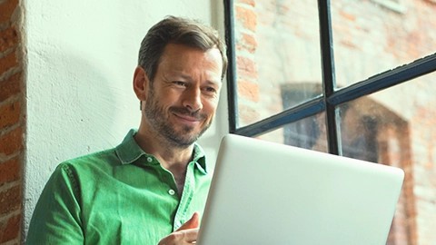 A business man wearing a green shirt using his computer.