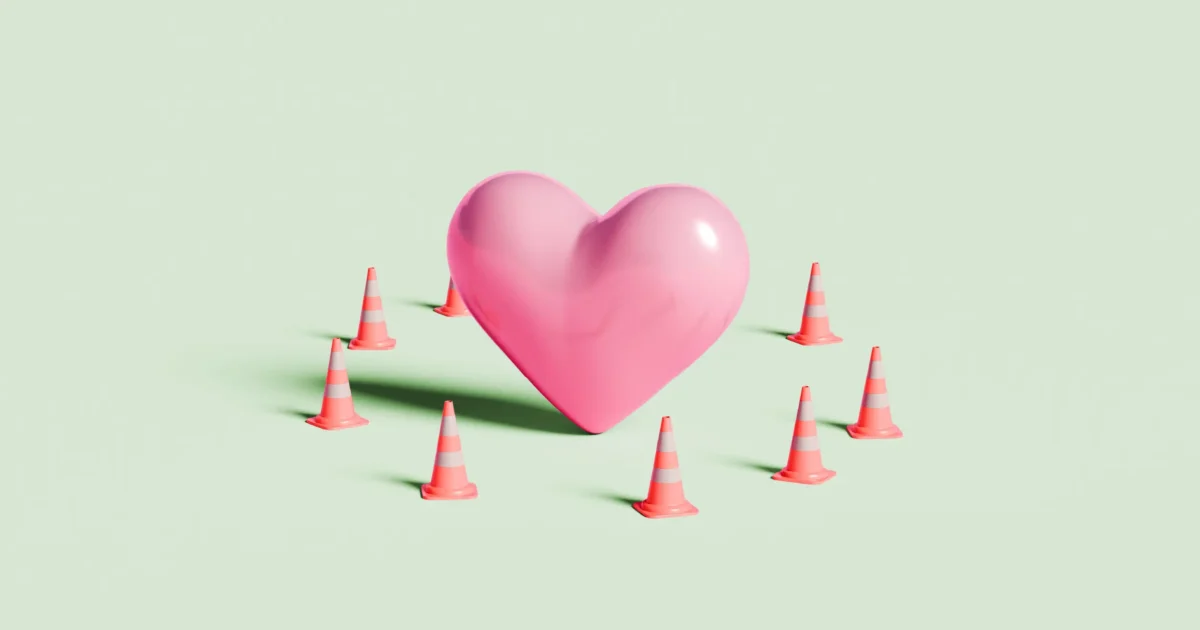 A large pink heart surrounded by small orange traffic cones on a light background.