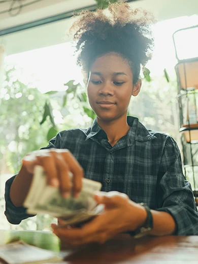 A woman wearing a plaid shirt, counting money.